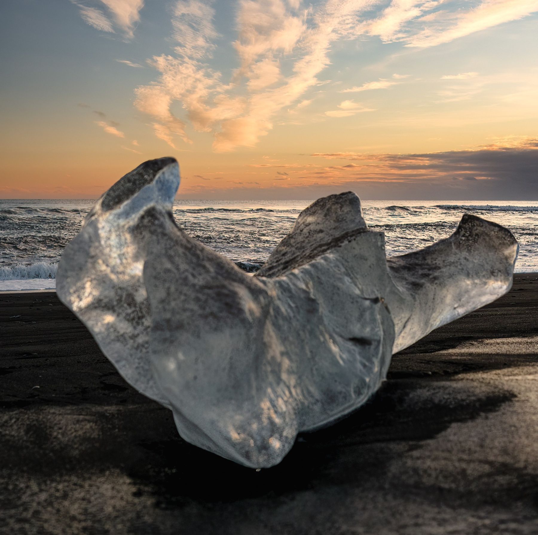 Blocco di ghiaccio sulla sabbia nera di Diamond Beach al tramonto, Islanda